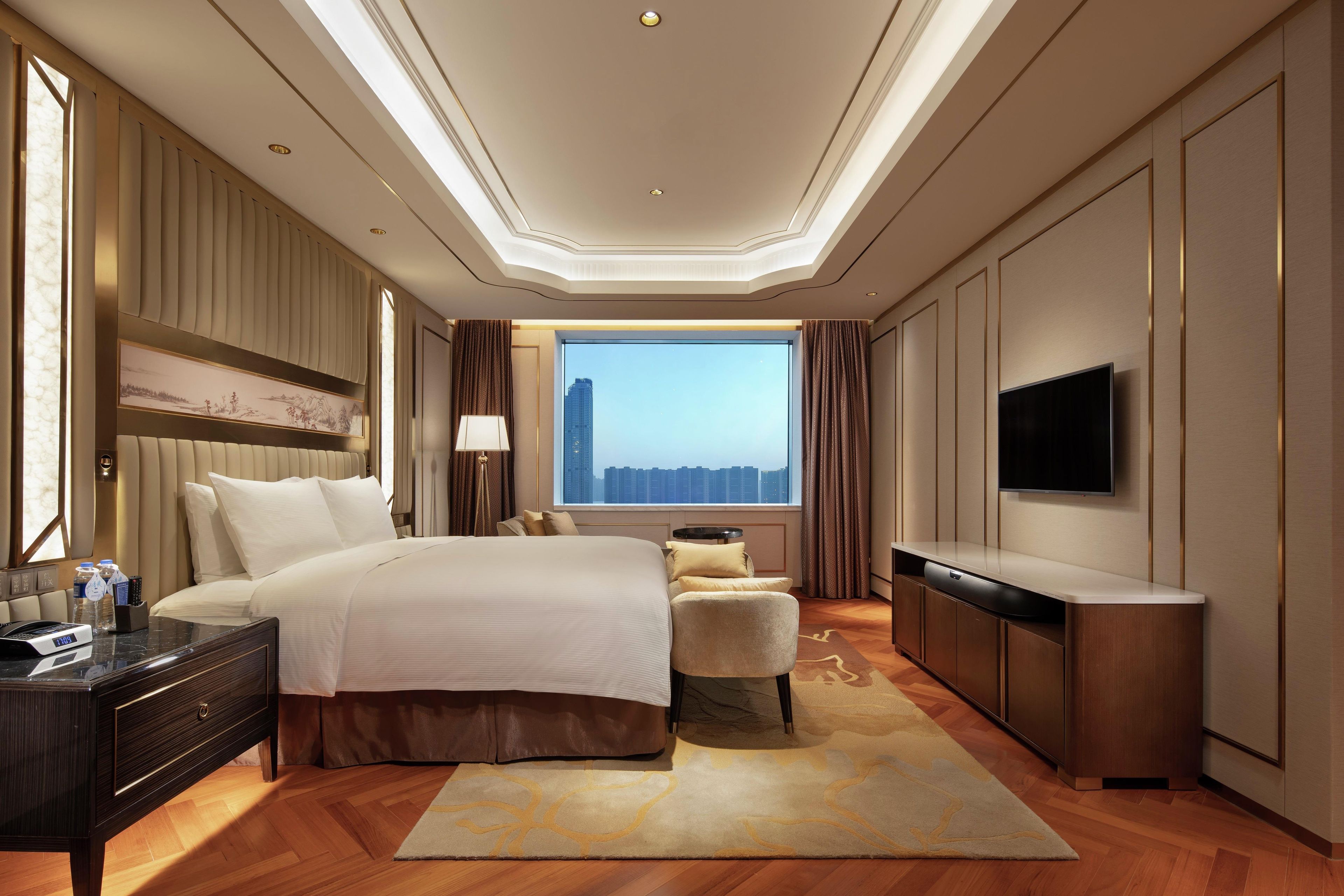 Habitación de hotel con una cama grande, un escritorio, un televisor y vistas a la ciudad.