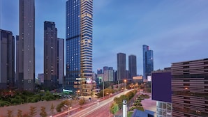 Ein Hochhaus-Hotel mit einem gut sichtbaren 'Hilton'-Schild, umgeben von weiteren hohen Gebäuden und einer belebten Straße mit Lichtspuren.