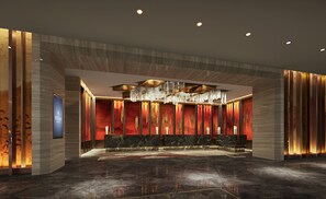 A modern hotel lobby with a marble reception desk, a large chandelier, and a red accent wall. - Hilton Shenyang (Shenyang)