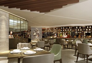 A modern restaurant with multiple dining tables, chairs, and a bar area with shelves of bottles. - Hilton Shenyang (Shenyang)