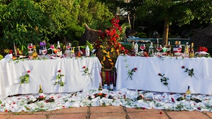 Una mesa dispuesta con botellas de vino y copas, rodeada de manteles blancos y rosas.