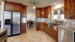 A kitchen with wooden cabinets, stainless steel appliances, and a tiled floor. - Sevier River Retreat (Hatch)