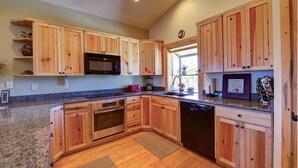 A kitchen with wooden cabinets, granite countertops, a microwave, oven, and dishwasher. - Ridgetop Hideaway (Hatch)