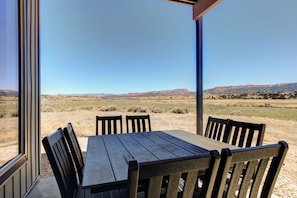 A table and chairs under a covered area with a view of a desert landscape. - The Lookout at Sevier River (Hatch)