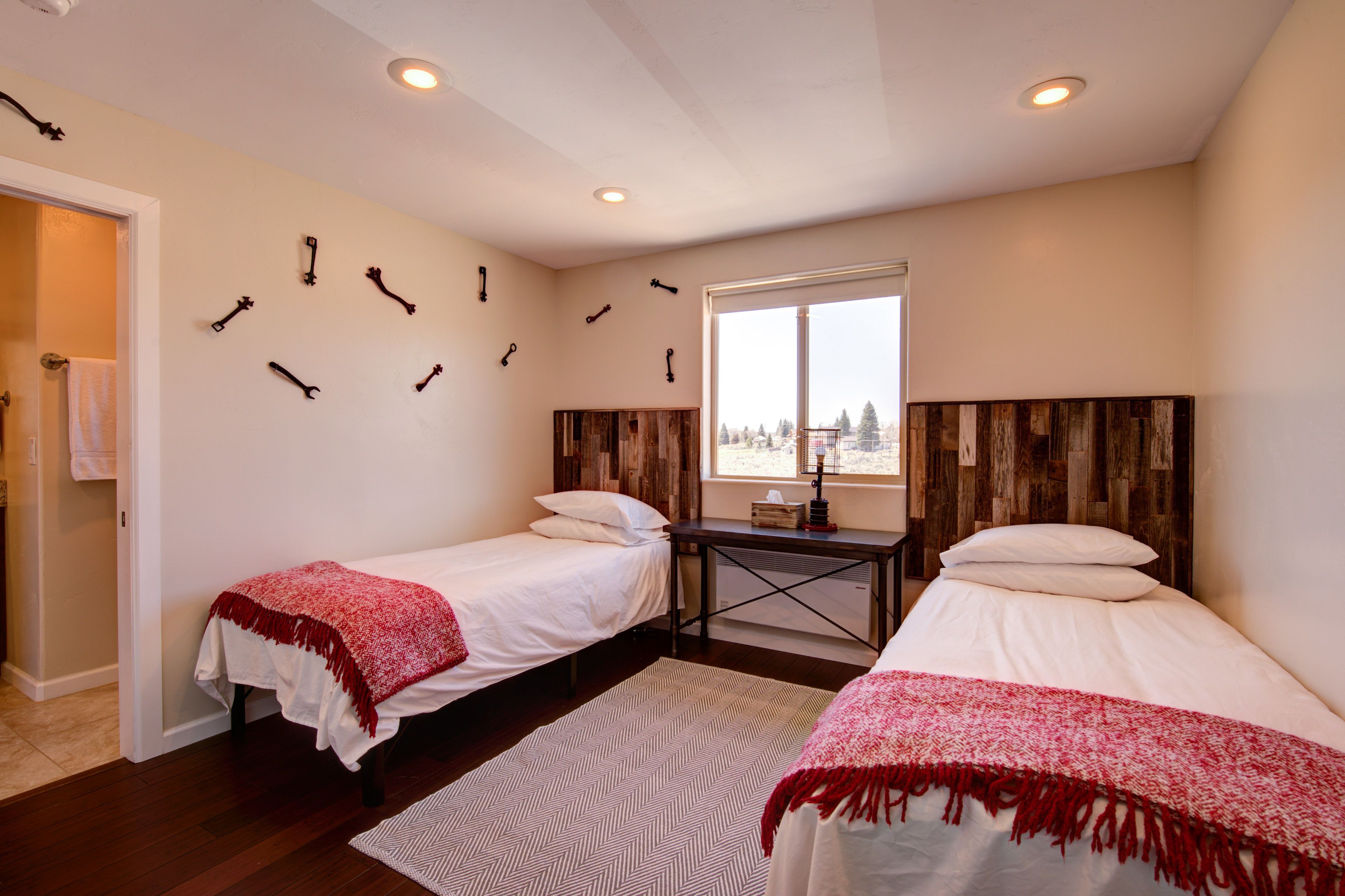 A room with two beds, a wooden headboard, a small table, and a window with a view.
