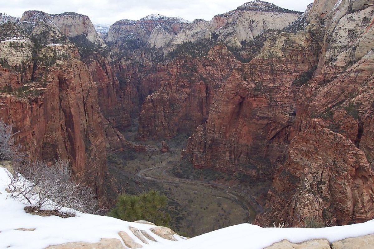 A canyon with steep red rock walls and a snow-covered foreground.