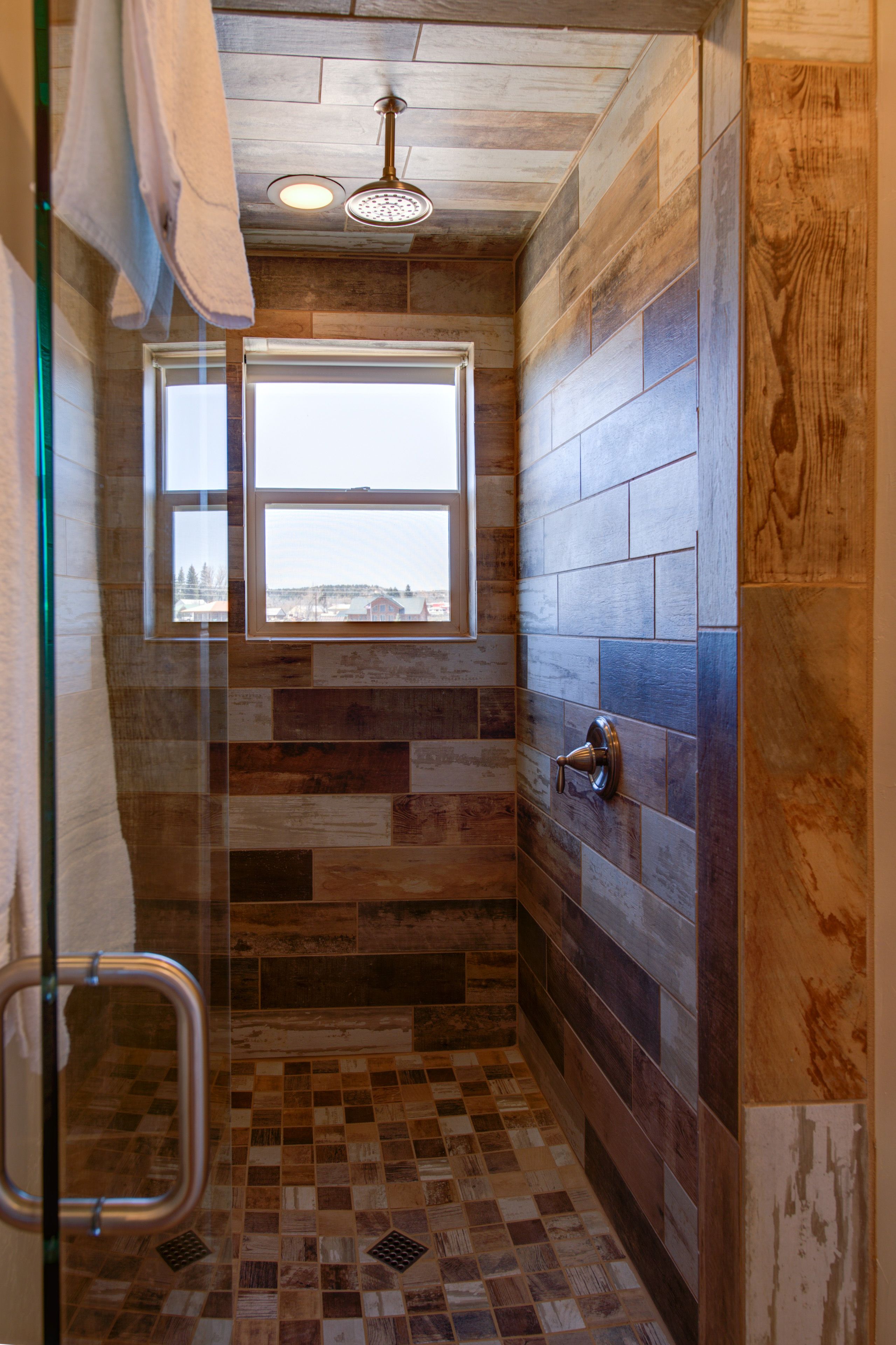 Ducha con ventana, azulejos de madera y puerta de cristal.