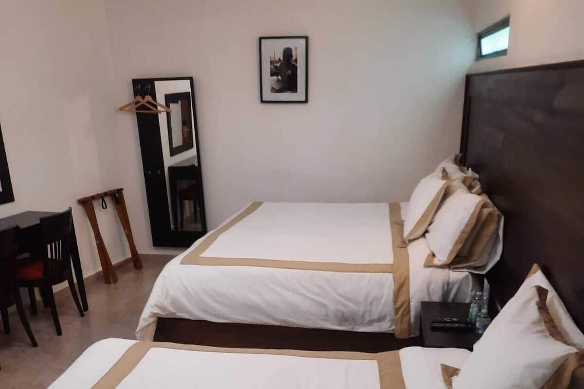 A hotel room with two beds, a desk, and a chair.