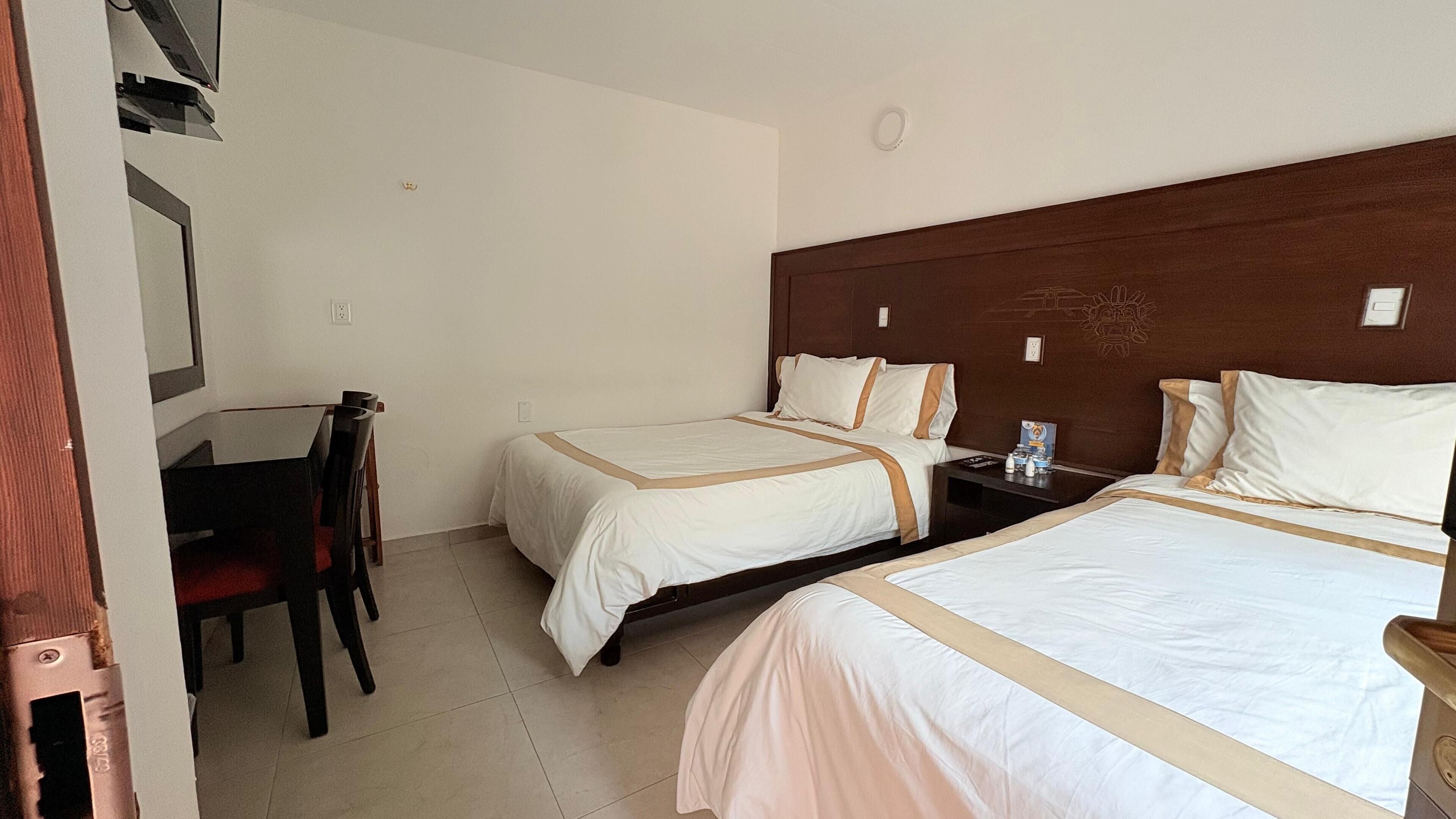Une chambre d’hôtel avec deux lits, un bureau et une chaise.