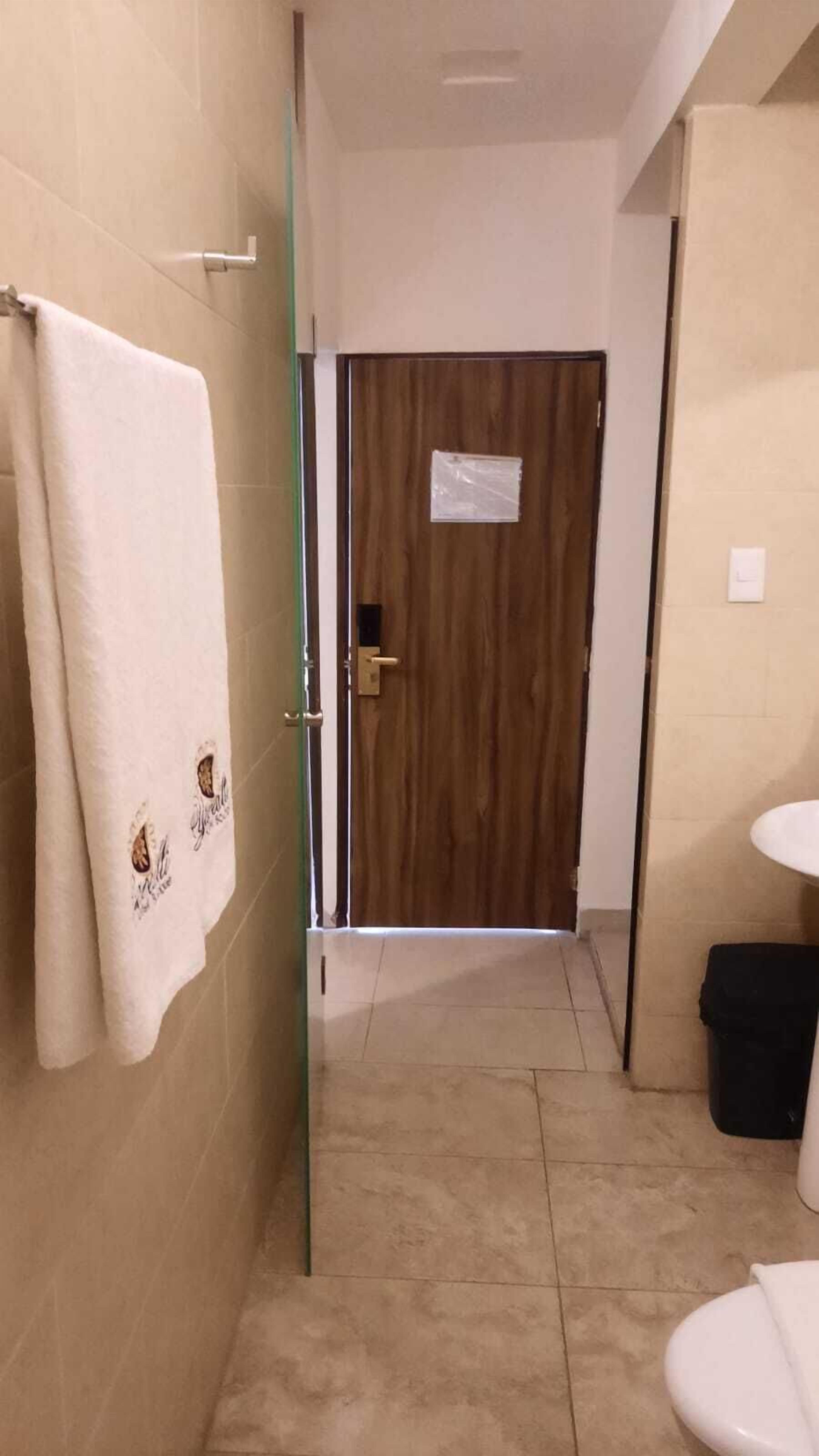 Un baño con una toalla colgada en la pared, una puerta de madera y un inodoro.