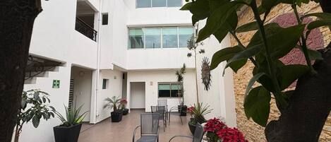 An outdoor patio area with potted plants and chairs.