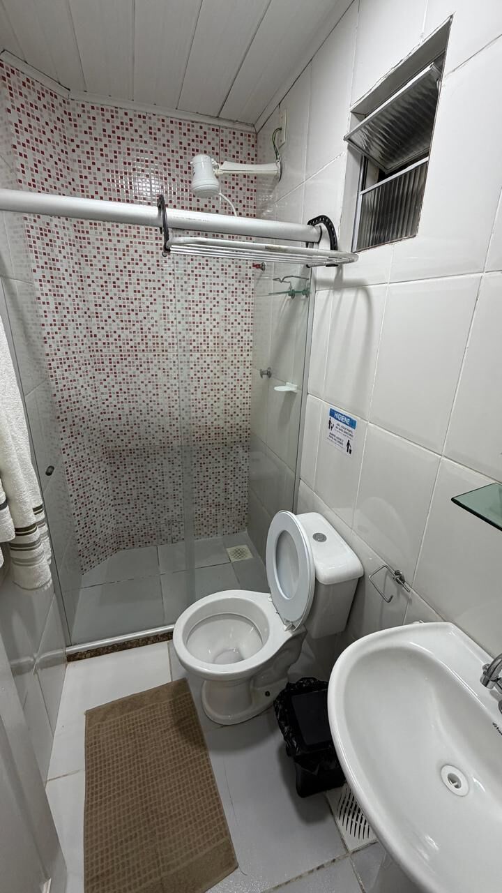 A bathroom with a shower, toilet, sink, and a window.