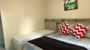 Quarto com uma cama de solteiro, cabeceira e um quadro na parede.