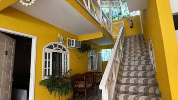A staircase with white railings leading to a second floor, a potted plant, and a door with a mat.
