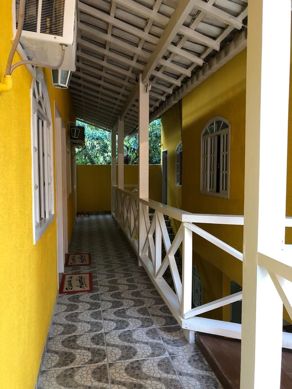 A corridor with a tiled floor, white railings, and a ceiling with a wooden beam structure.
