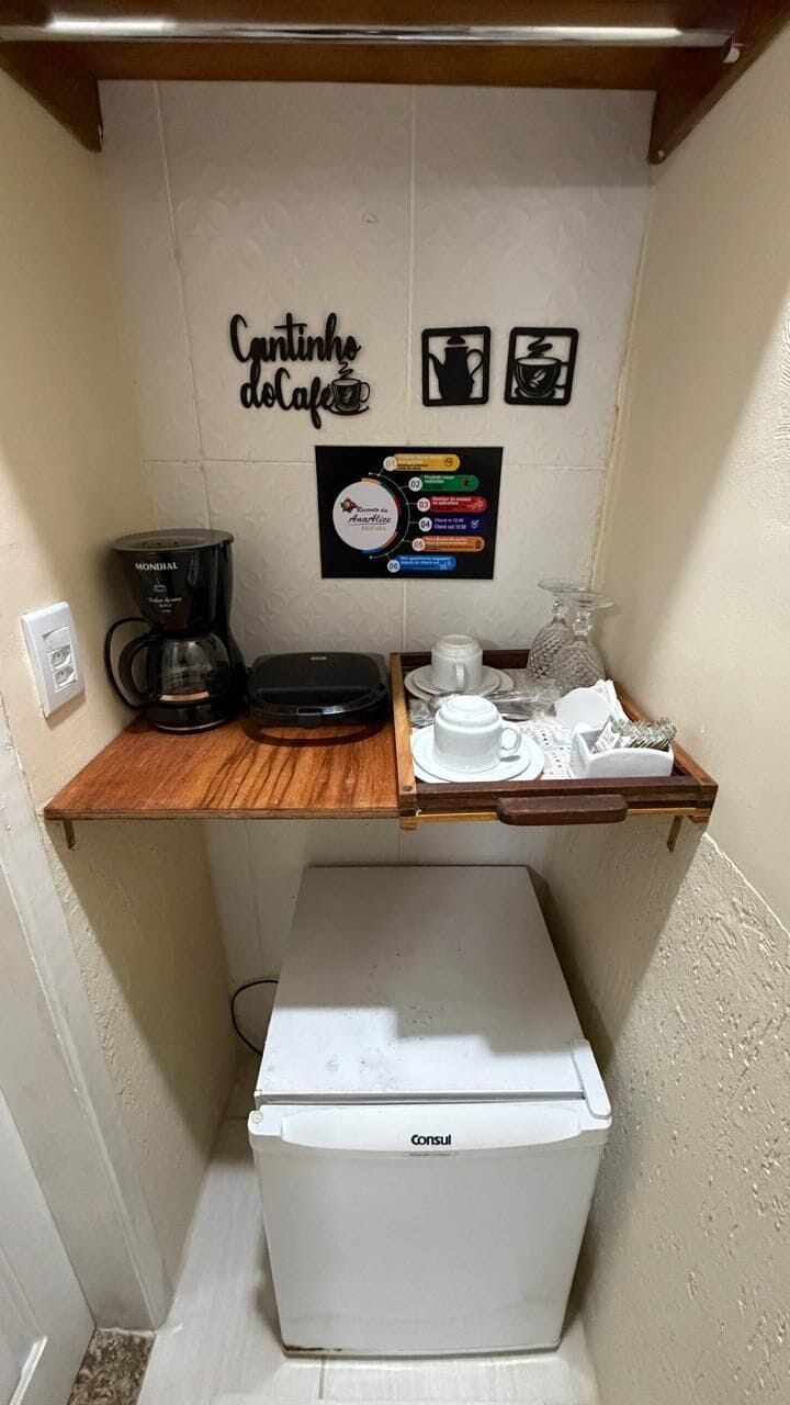 Une petite cuisine équipée d’une machine à café, d’un réfrigérateur et d’un espace dédié à la préparation du café.