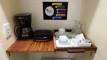 Une petite cuisine équipée d’une machine à café, d’un réfrigérateur et d’un espace dédié à la préparation du café.