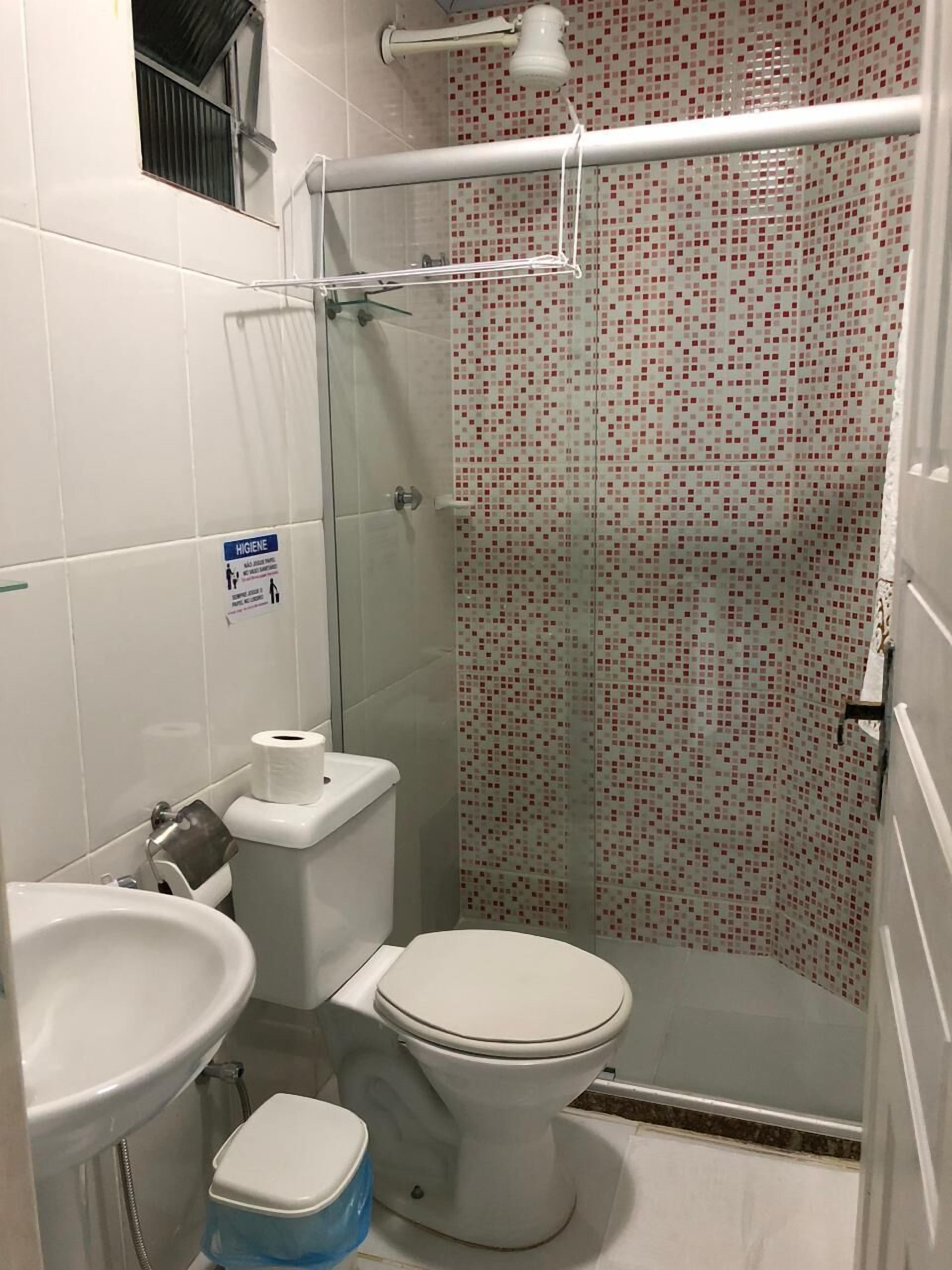 Un baño pequeño con inodoro, lavamanos y ducha.