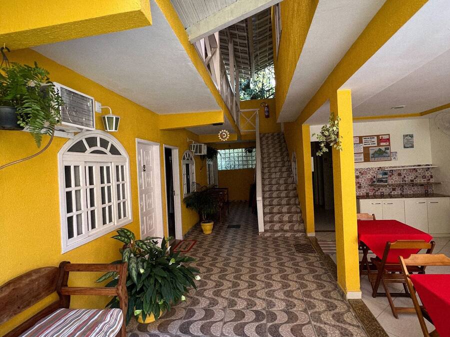A spacious indoor area with a tiled floor, wooden benches, and tables with red tablecloths.