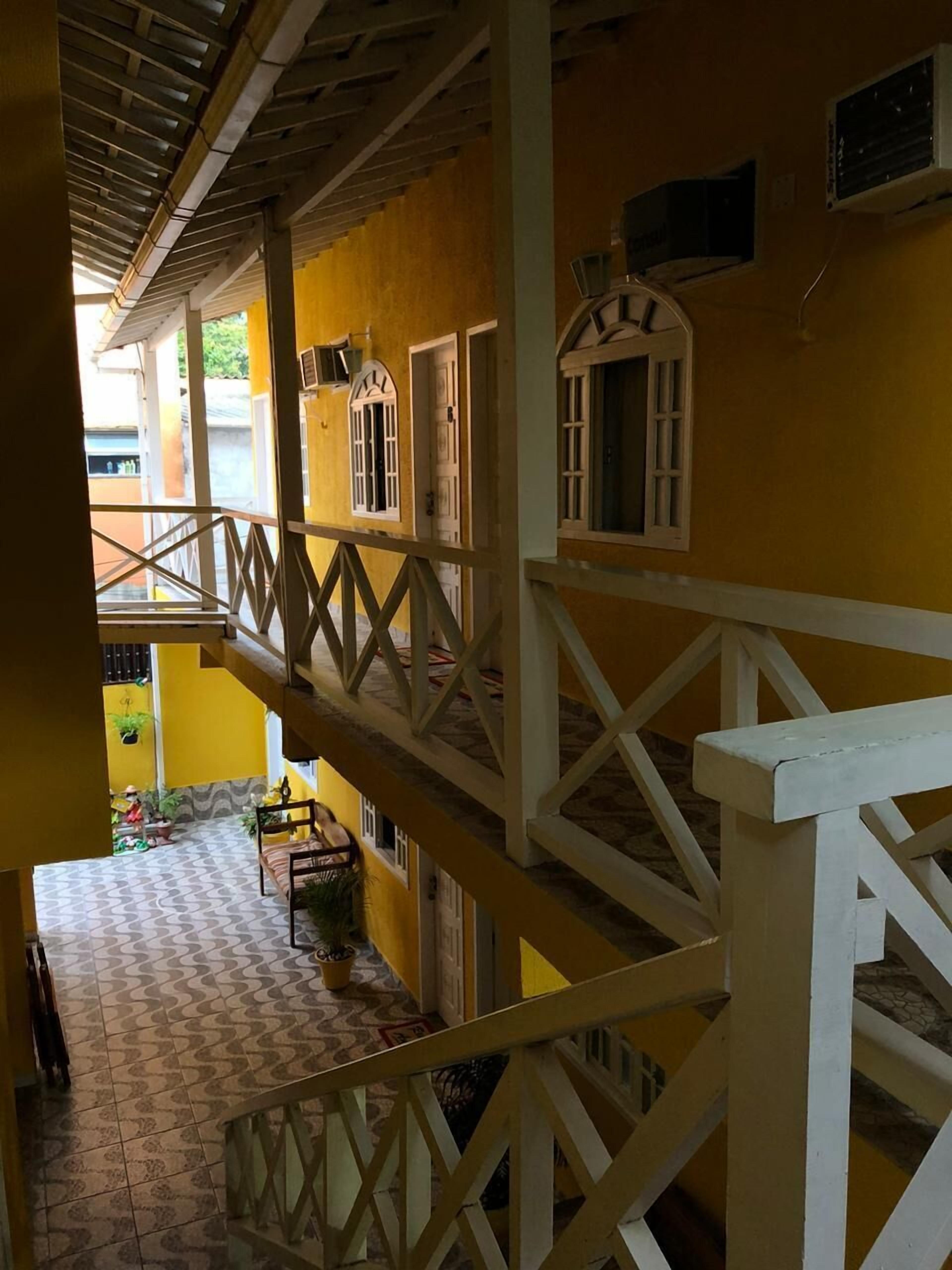 Un edificio de varios niveles con balcón, suelo de baldosas y fachada amarilla.