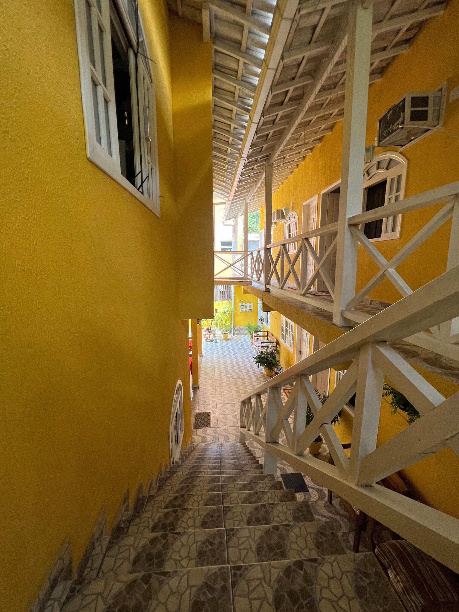 Una escalera estrecha con suelo de baldosas estampadas que lleva a un balcón.