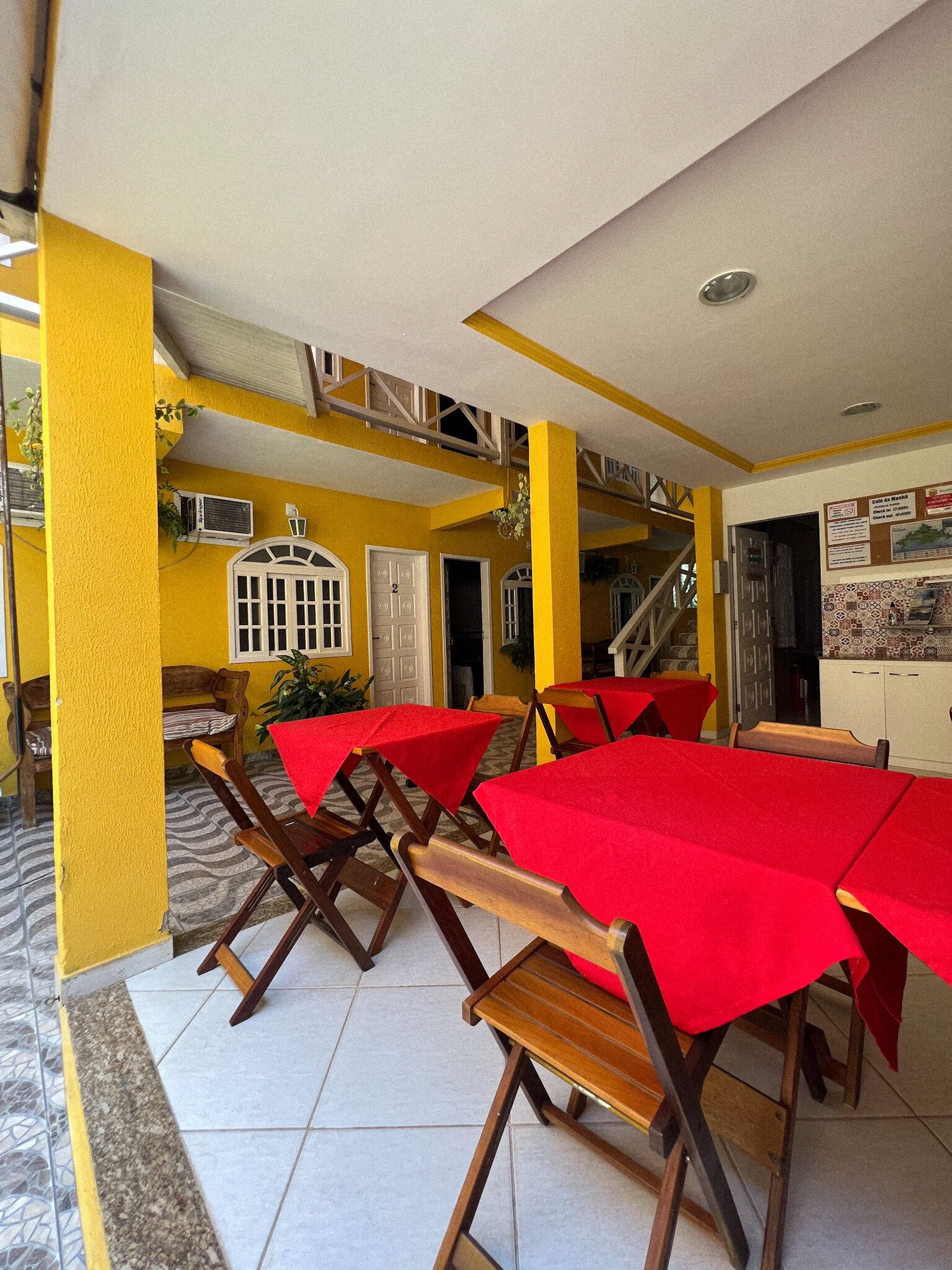 Un restaurante con paredes amarillas, manteles rojos y sillas de madera.