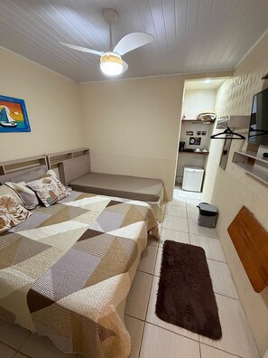 A compact room with a bed, a small kitchenette, a ceiling fan, and a trash bin. - Recanto da Ana Alice (Angra dos Reis)