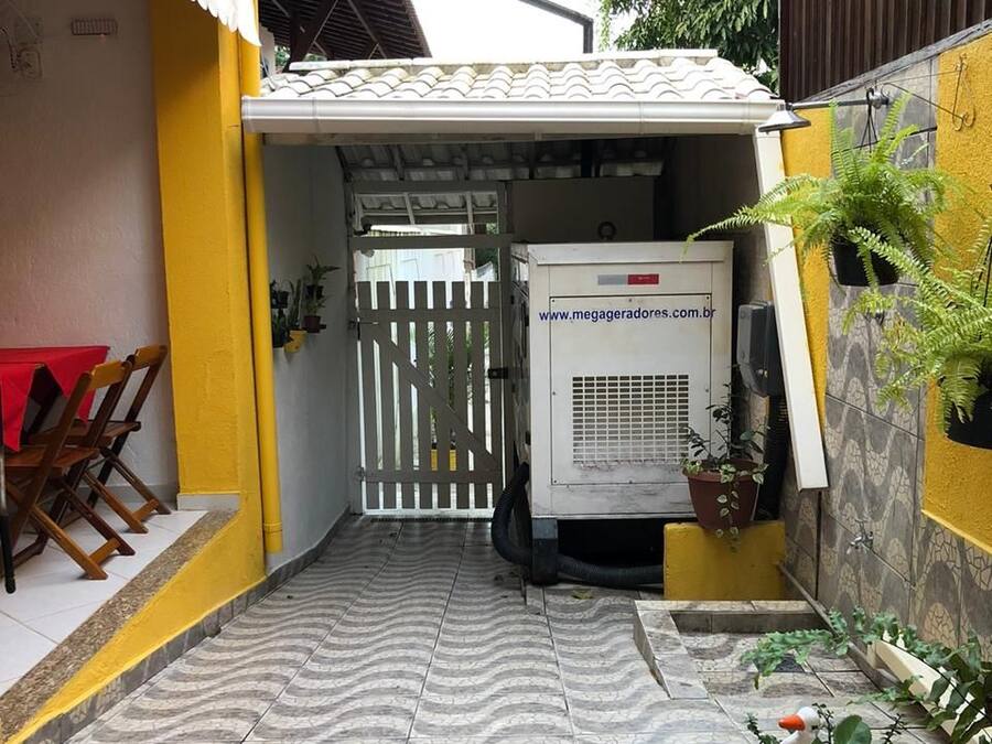 A narrow outdoor corridor with tiled flooring, a white air conditioning unit, and a yellow wall.