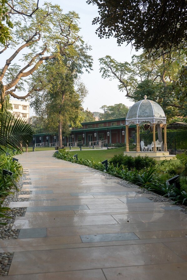 A pathway leading to a building with a gazebo, surrounded by greenery and trees. - Narain Niwas Palace (Jaipur)