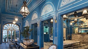 A hotel lobby with a checkered floor, blue walls, ornate ceiling designs, and chandeliers. - Narain Niwas Palace (Jaipur)