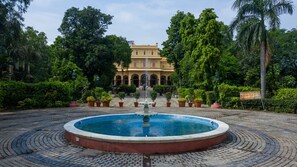 A courtyard with a fountain, potted plants, and a building with arches. - Narain Niwas Palace (Jaipur)