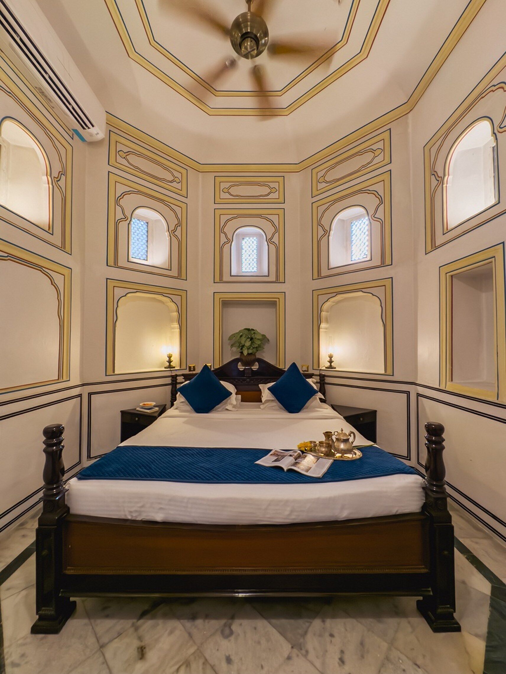Une chambre dotée d’un grand lit, d’un ventilateur de plafond et de plusieurs petites fenêtres.
