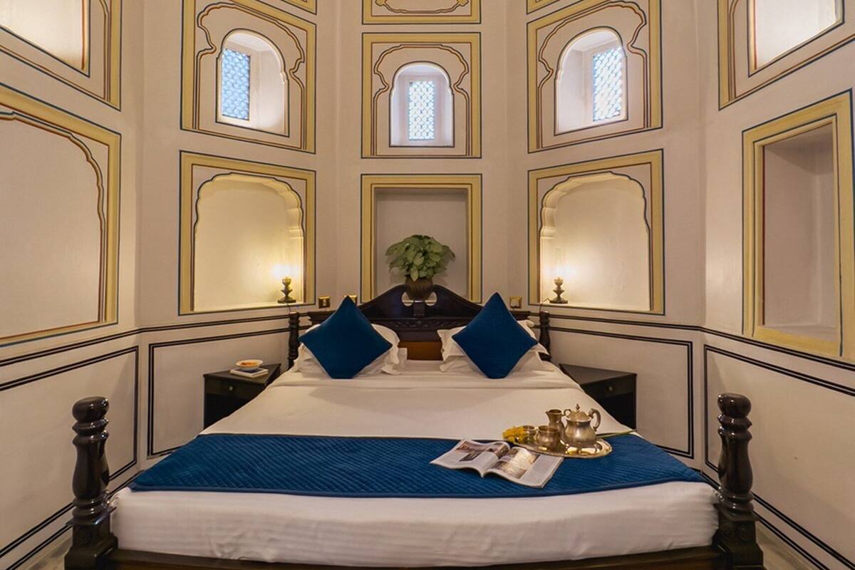 Une chambre dotée d’un grand lit, d’un ventilateur de plafond et de plusieurs petites fenêtres.