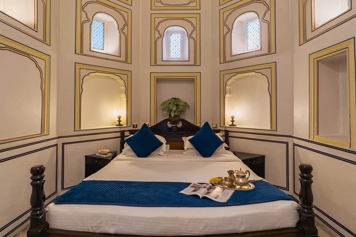 A room with a large bed, a ceiling fan, and multiple small windows.