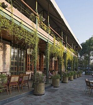 A building with a covered outdoor seating area, stone walls, and potted plants. - Narain Niwas Palace (Jaipur)