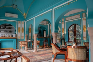 Ein Zimmer mit türkisfarbenen Wänden, Holzmöbeln und einem gemusterten Teppich.