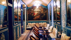 A restaurant with a mural, booths, and a checkered floor. - Narain Niwas Palace (Jaipur)