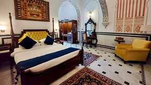 A room with a bed, a yellow armchair, a wardrobe, and a mirror. - Narain Niwas Palace (Jaipur)