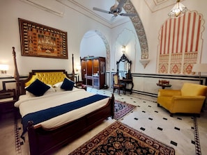 Una habitación con una cama, un sillón amarillo, un armario y un espejo.