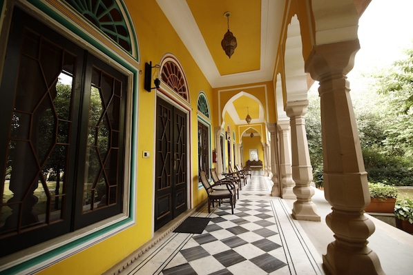 A corridor with a checkered floor, arched windows, and columns.