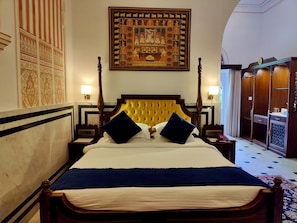 A four-poster bed with a yellow headboard, two blue pillows, and a white bedspread.