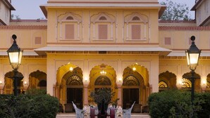 A grand building with multiple arches and a central entrance, surrounded by potted plants and a paved walkway. - Narain Niwas Palace (Jaipur)