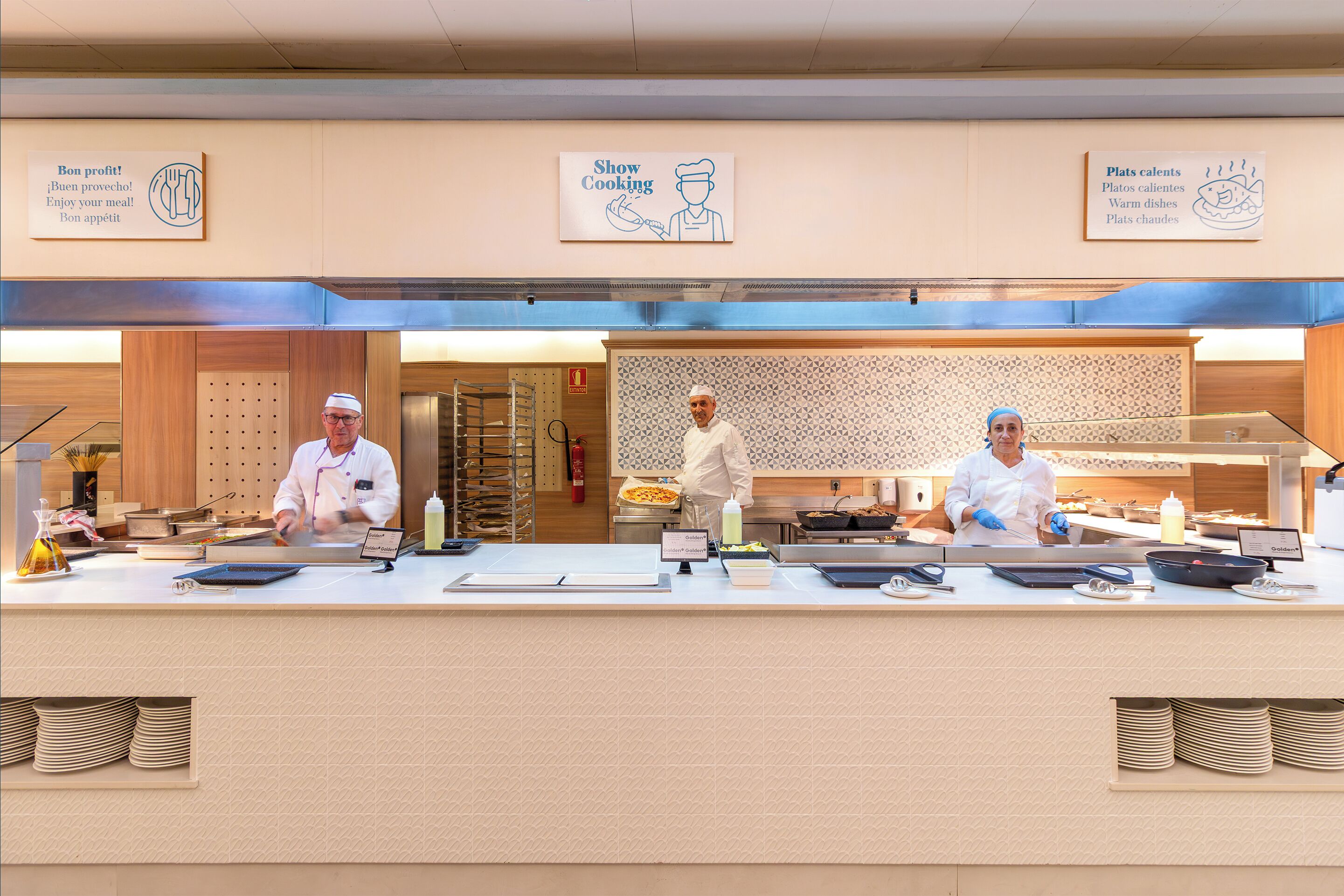 A buffet setup with three chefs, a fire extinguisher, and a sign indicating 'Show Cooking'.
