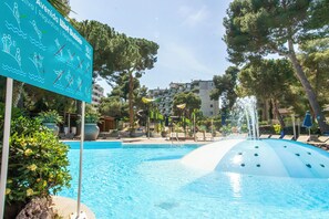 A swimming pool with a water slide, lounge chairs, and a sign with swimming instructions. - Golden Avenida Family Suites (Salou)
