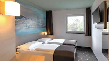 A hotel room with two beds, a desk, a painting, a window, and a TV.