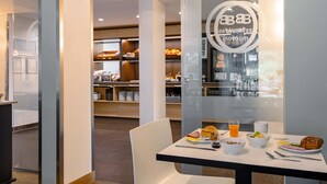 A breakfast area with a table set for two, including breakfast items like pancakes, a muffin, and a glass of orange juice. - B&B HOTEL Koblenz-City (Koblenz)