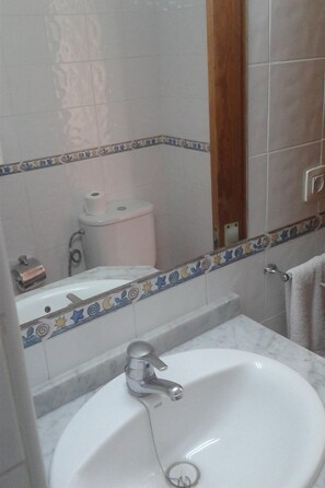 A bathroom with a white sink, a toilet, and a mirror. - Isla Bonita Apartamentos (Mogan)