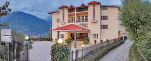 A two-story building with a red roof, a gated entrance, and a signboard. - Club Mahindra Snowpeaks Resorts (Manali)
