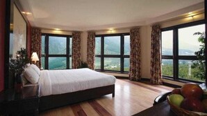 Une chambre à coucher avec un grand lit, de nombreuses fenêtres et une vue sur l’extérieur.