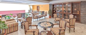 A spacious lobby with striped armchairs, a central coffee table, and a bookshelf.